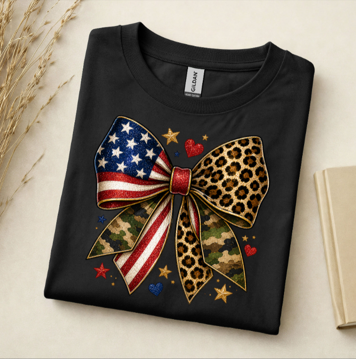 Black t-shirt with a colorful bow design featuring American flag, camouflage, and leopard print