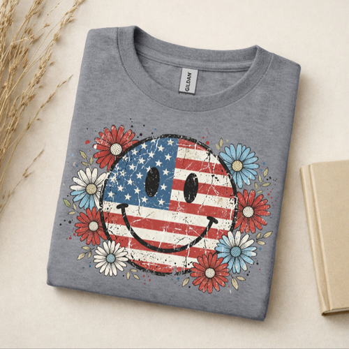 Folded gray t-shirt with American flag smiley face design on a light background