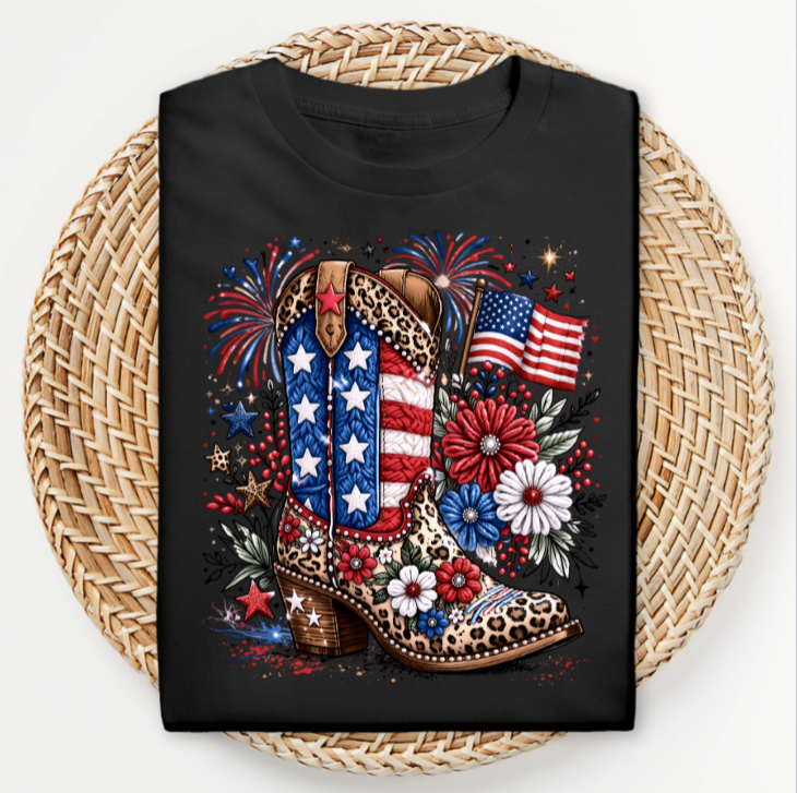 Black t-shirt with a colorful design of cowboy boots, American flag, and fireworks