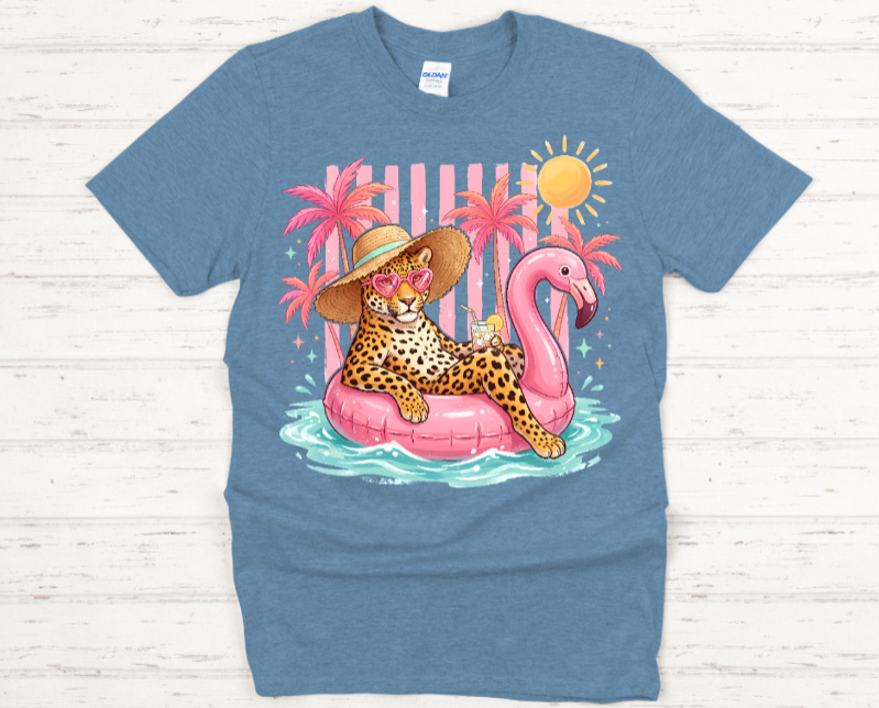 Blue t-shirt with a colorful graphic of a leopard on a pink flamingo float, palm trees, and a sun.