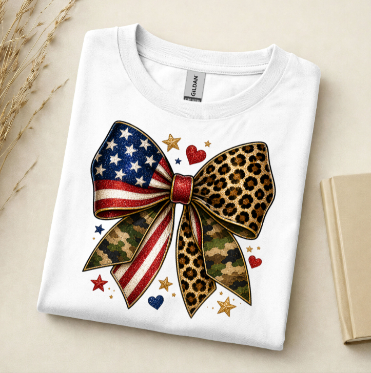 White t-shirt with a colorful bow design featuring American flag, leopard print, and camouflage